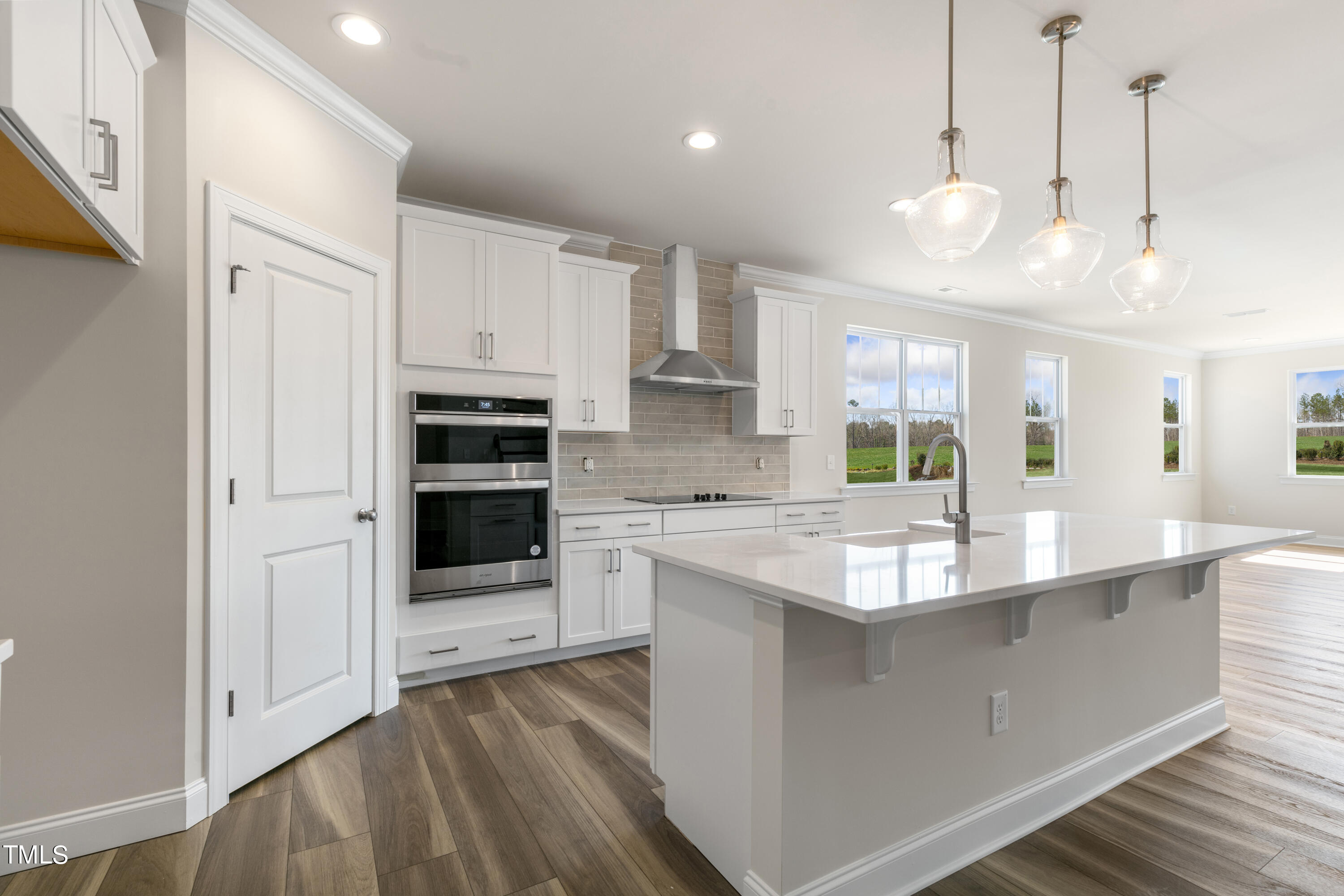 a large kitchen with kitchen island a stove a sink a center island and wooden floor