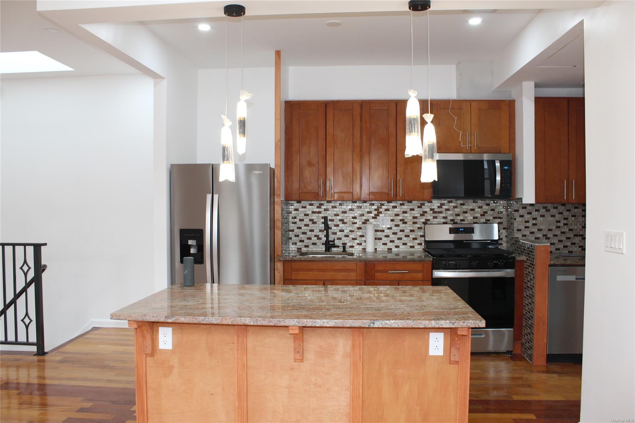 Kitchen with decorative backsplash, hanging light fixtures, sink, and appliances with stainless steel finishes