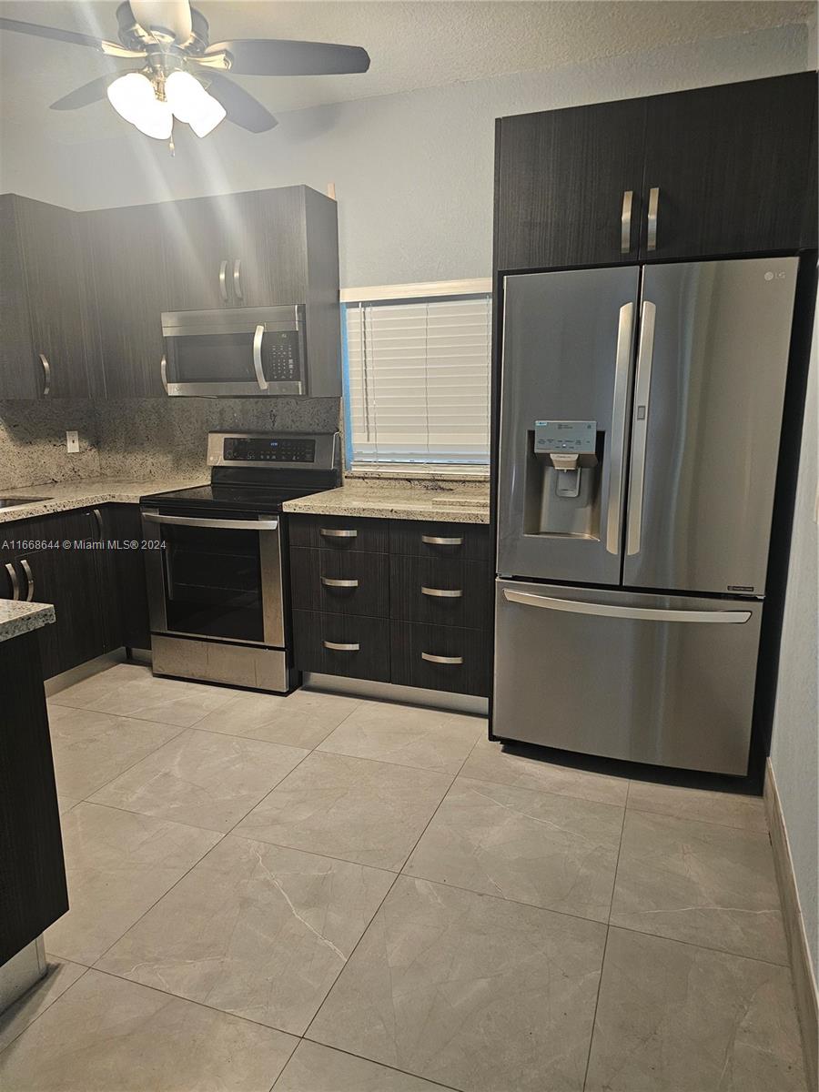 a large kitchen with granite countertop a refrigerator and a sink