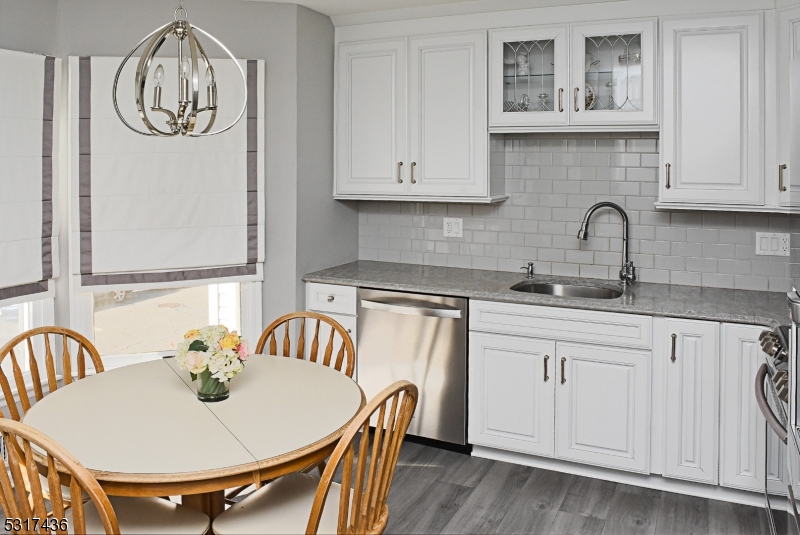 a kitchen with stainless steel appliances granite countertop a white table and chairs