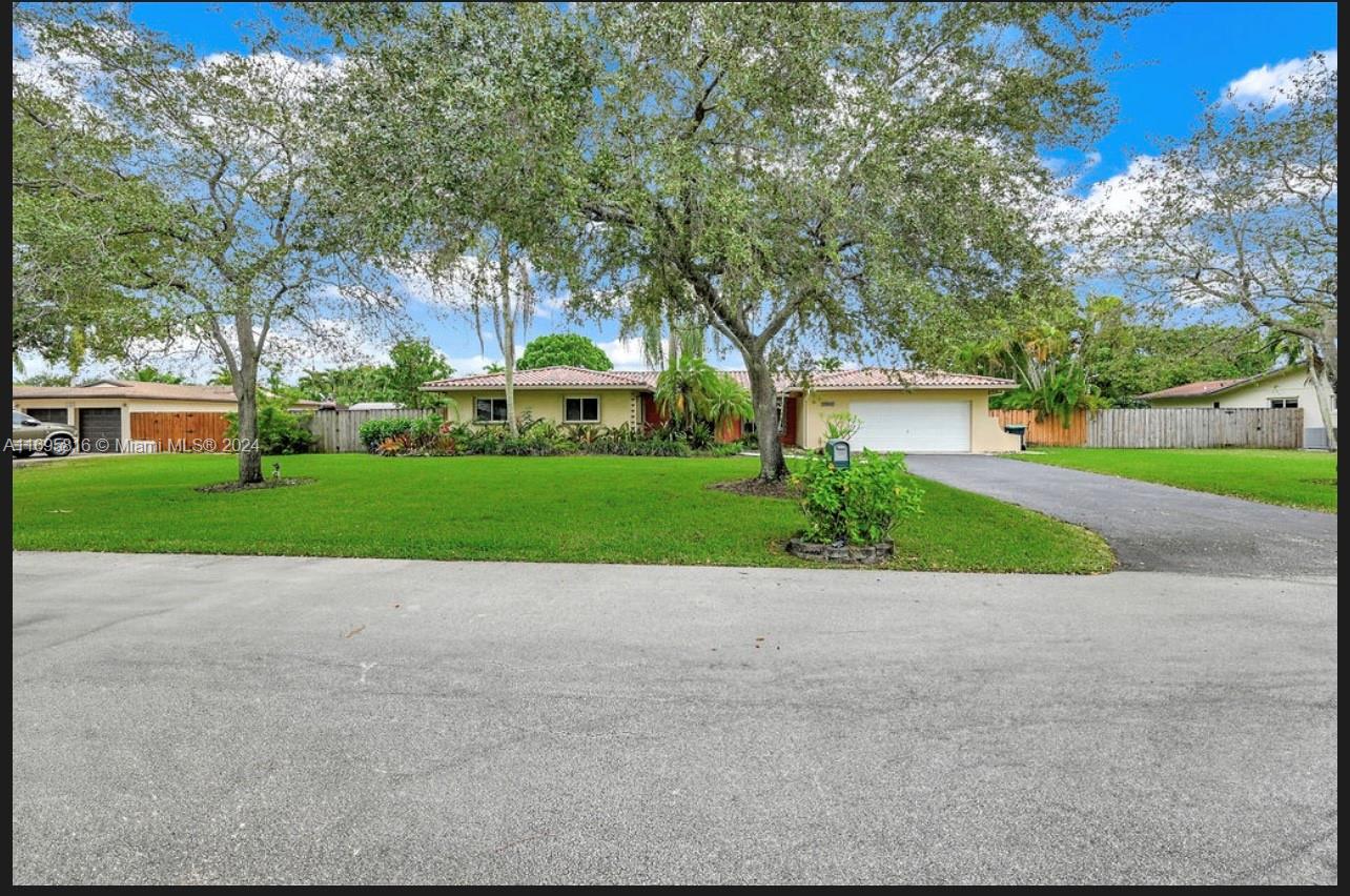 a view of a house with a yard and large tree