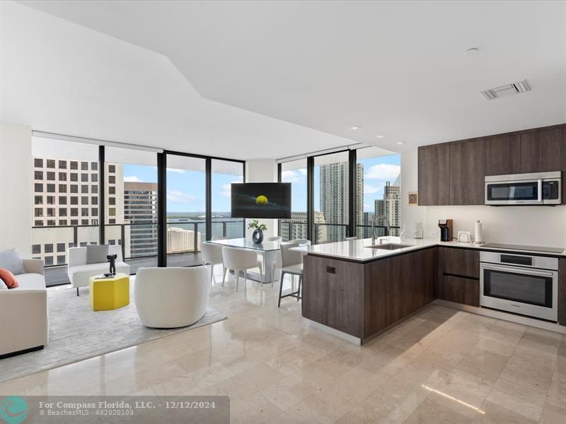 a large white kitchen with a large window and stainless steel appliances