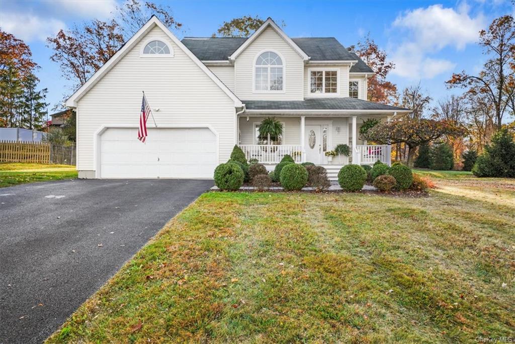 View of front of property featuring a front lawn, a garage, and covered porch