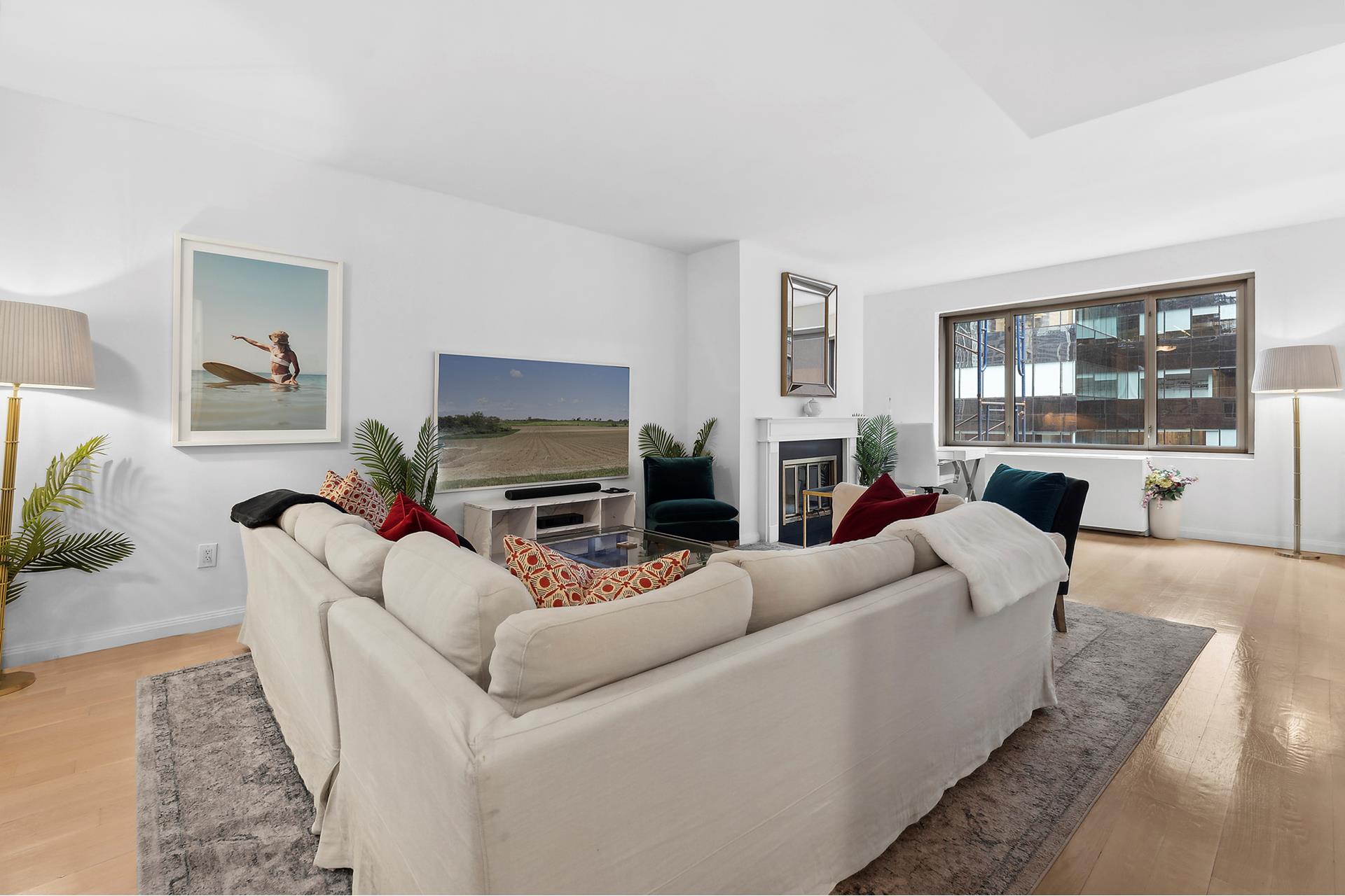 a living room with furniture a fireplace a flat screen tv and windows