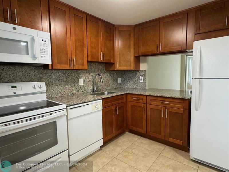 a kitchen with stainless steel appliances granite countertop wooden cabinets a stove a sink and dishwasher