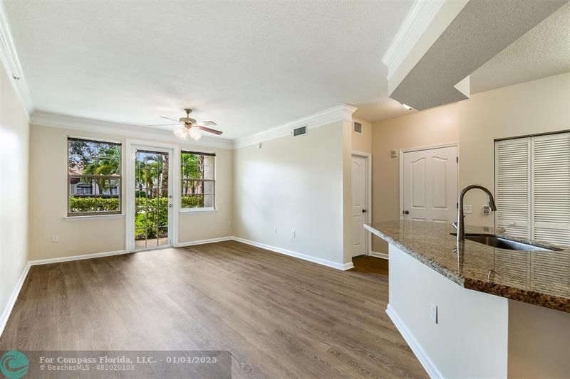 a view of a kitchen with granite countertop a sink and dishwasher with wooden floor