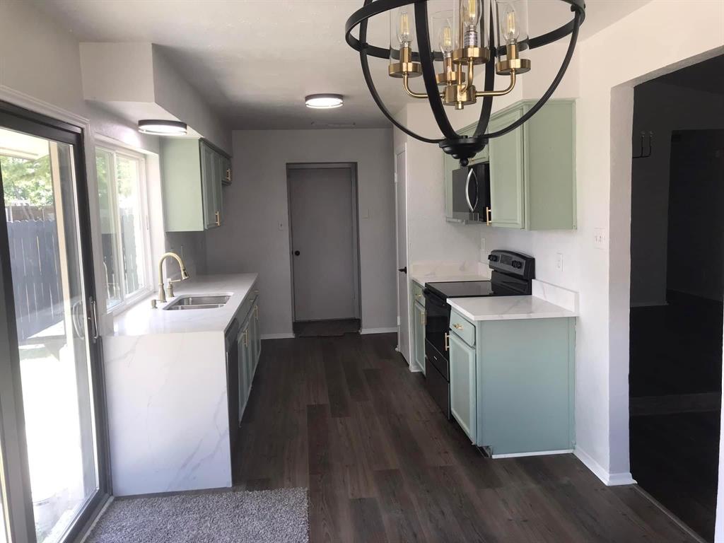 a kitchen with stainless steel appliances a sink a refrigerator and a hard wood floor