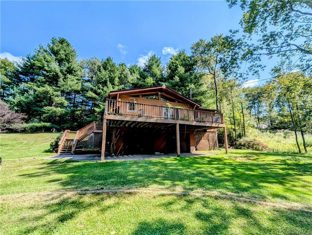 Side of property featuring a yard and a deck