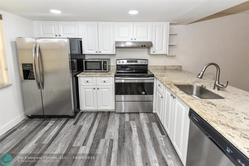 a kitchen with granite countertop a sink stove and refrigerator