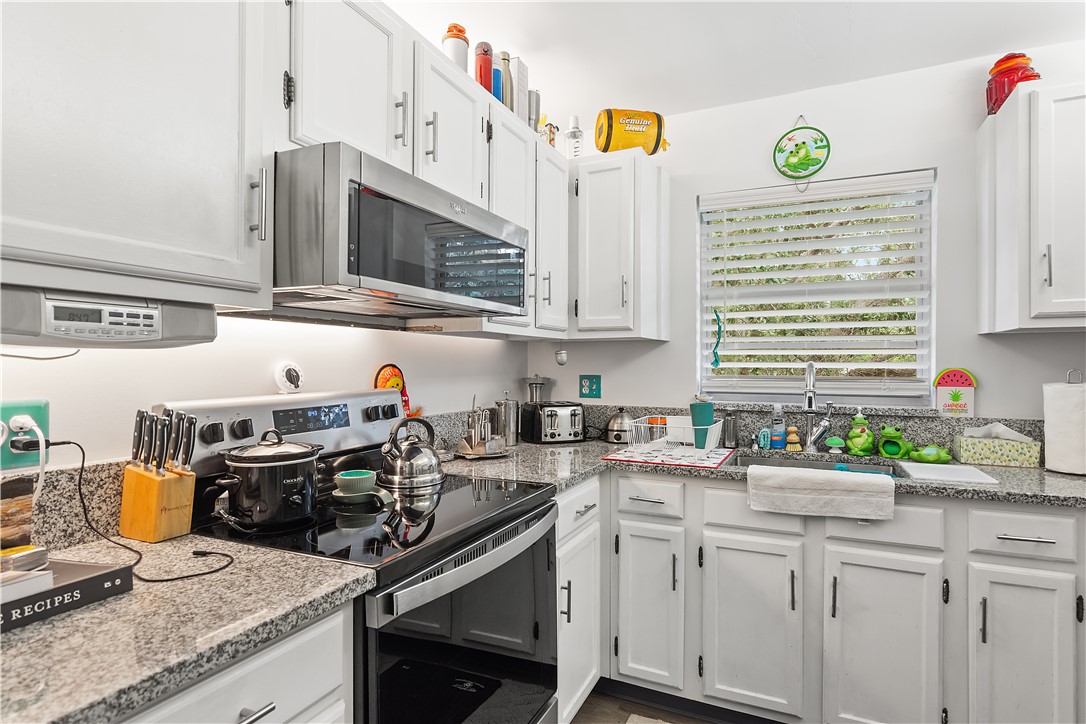 a kitchen with stainless steel appliances granite countertop a sink a stove and a microwave