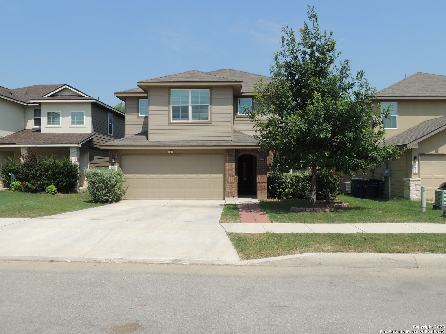 a front view of a house with a yard and trees