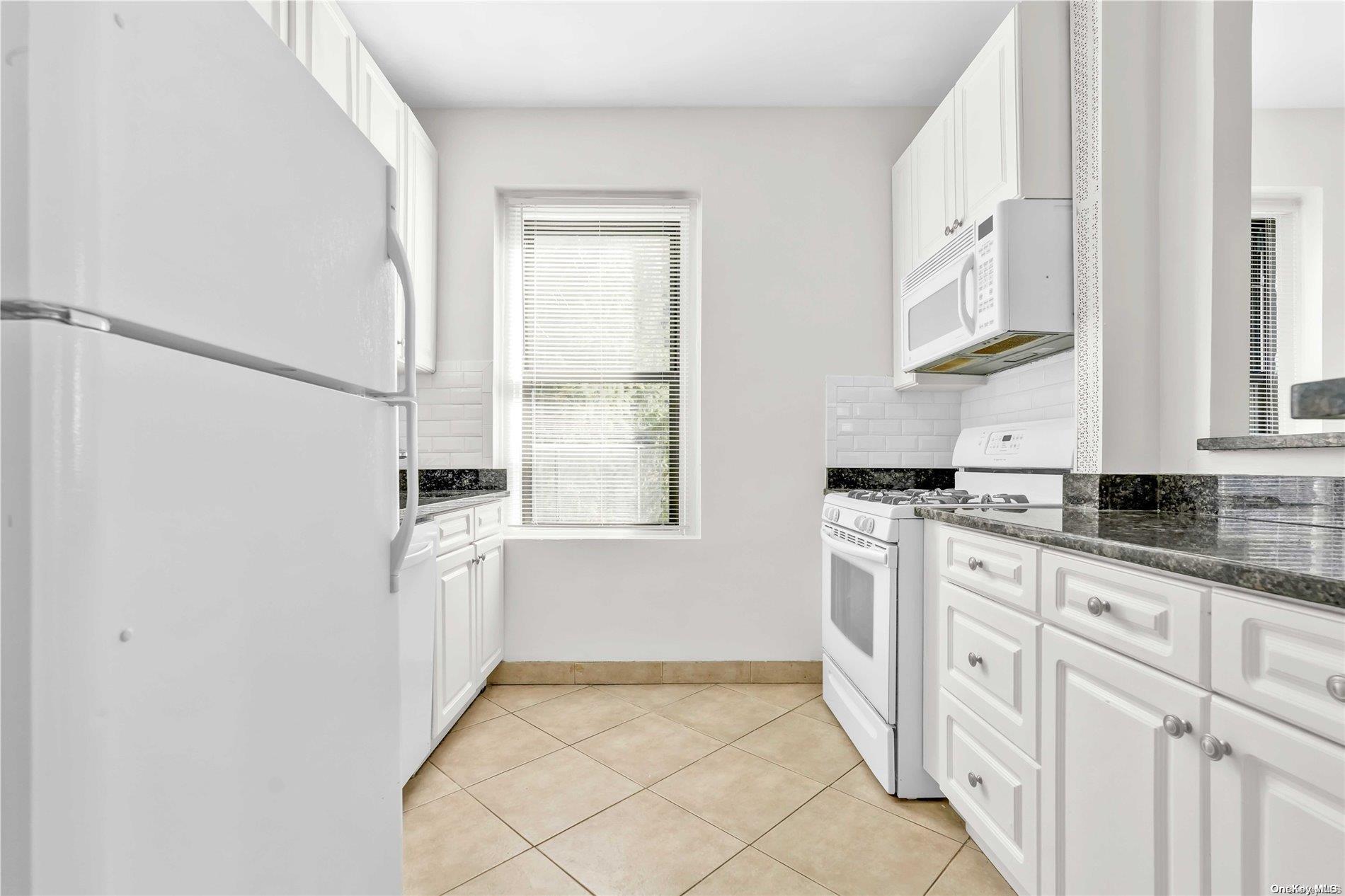 a kitchen with white cabinets and white appliances