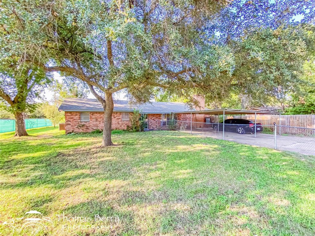 a view of a house with backyard and a tree