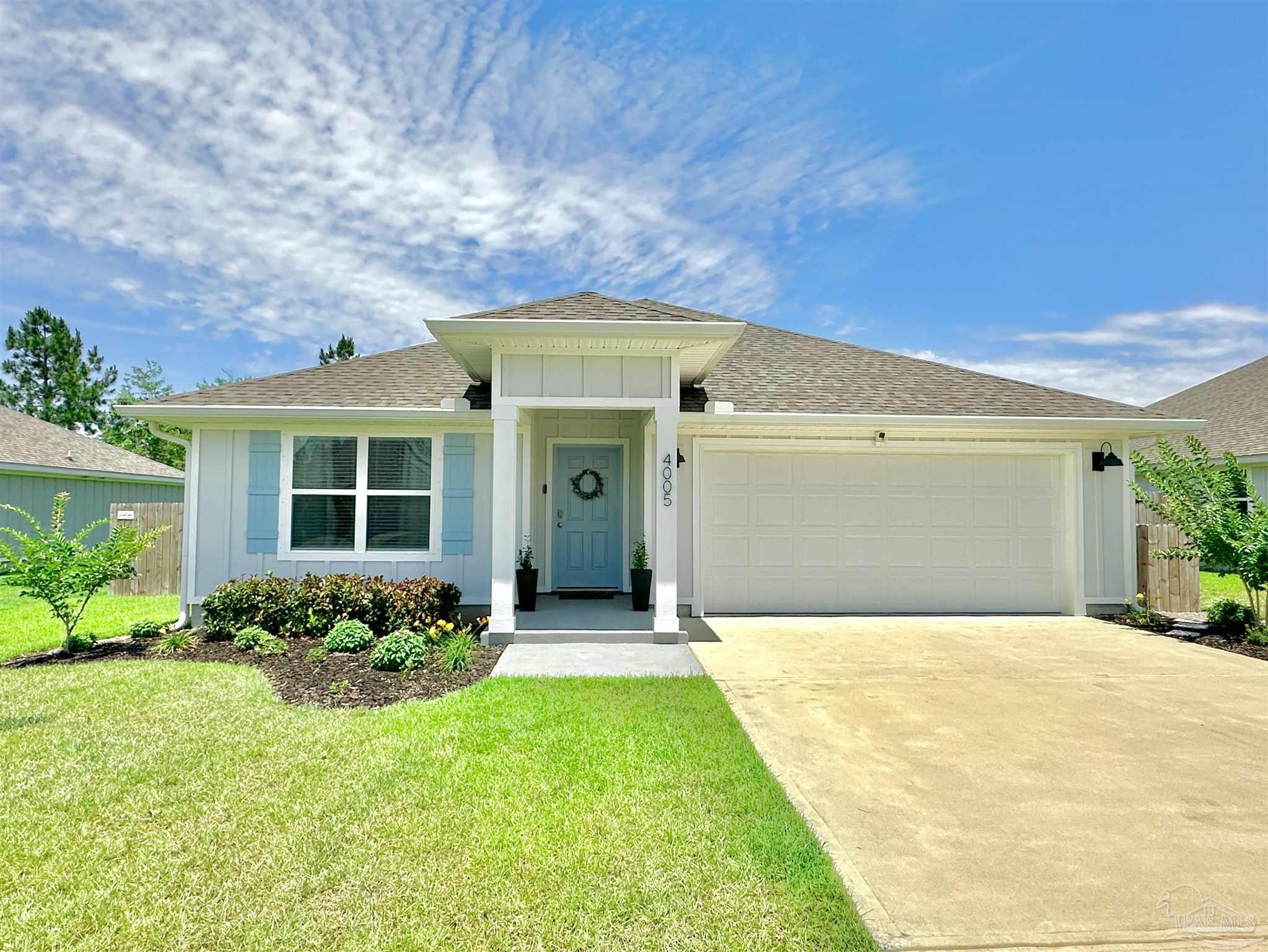 a front view of a house with a yard and potted plants