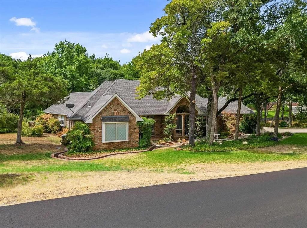 a front view of a house with a yard and large trees