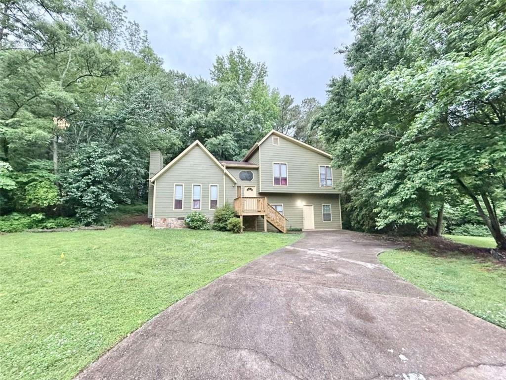 a view of a house with a yard and large trees