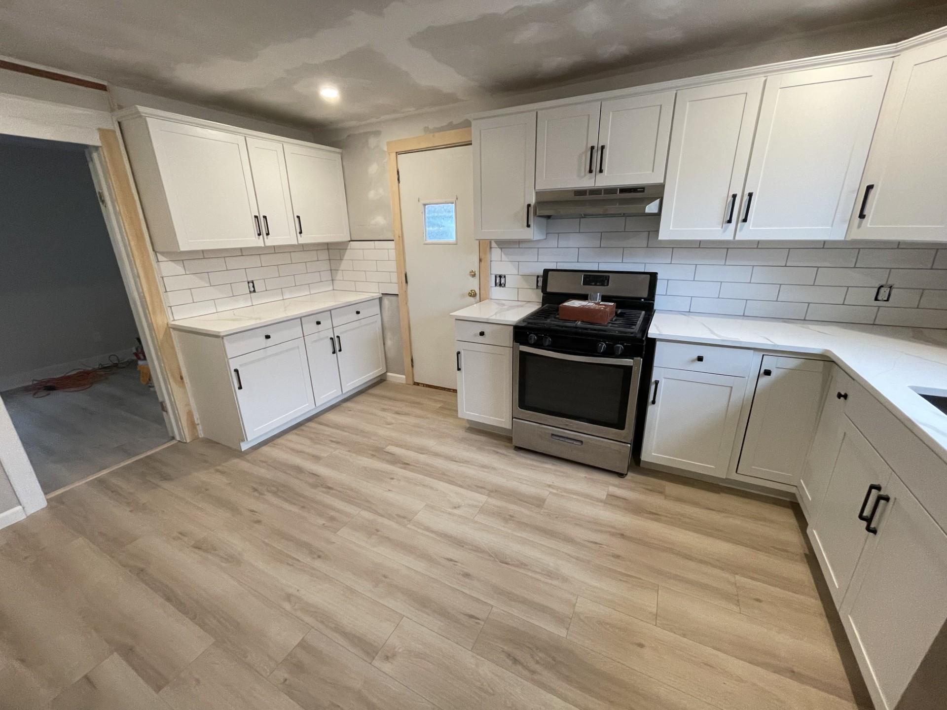 Kitchen featuring light wood-type flooring, white cabinetry, tasteful backsplash, and gas range