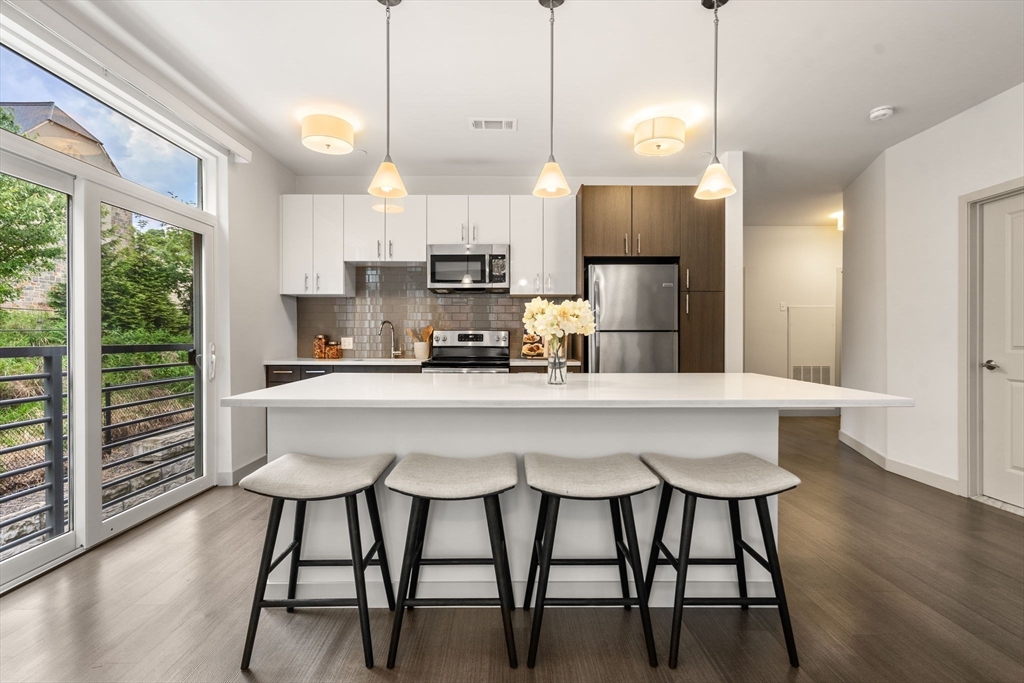 a kitchen with kitchen island a dining table chairs and a wooden floor