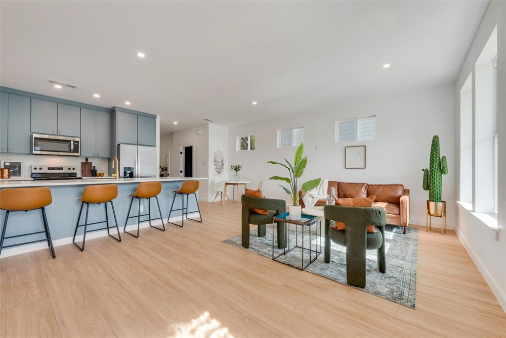 a living room with lots of furniture kitchen view and a wooden floor