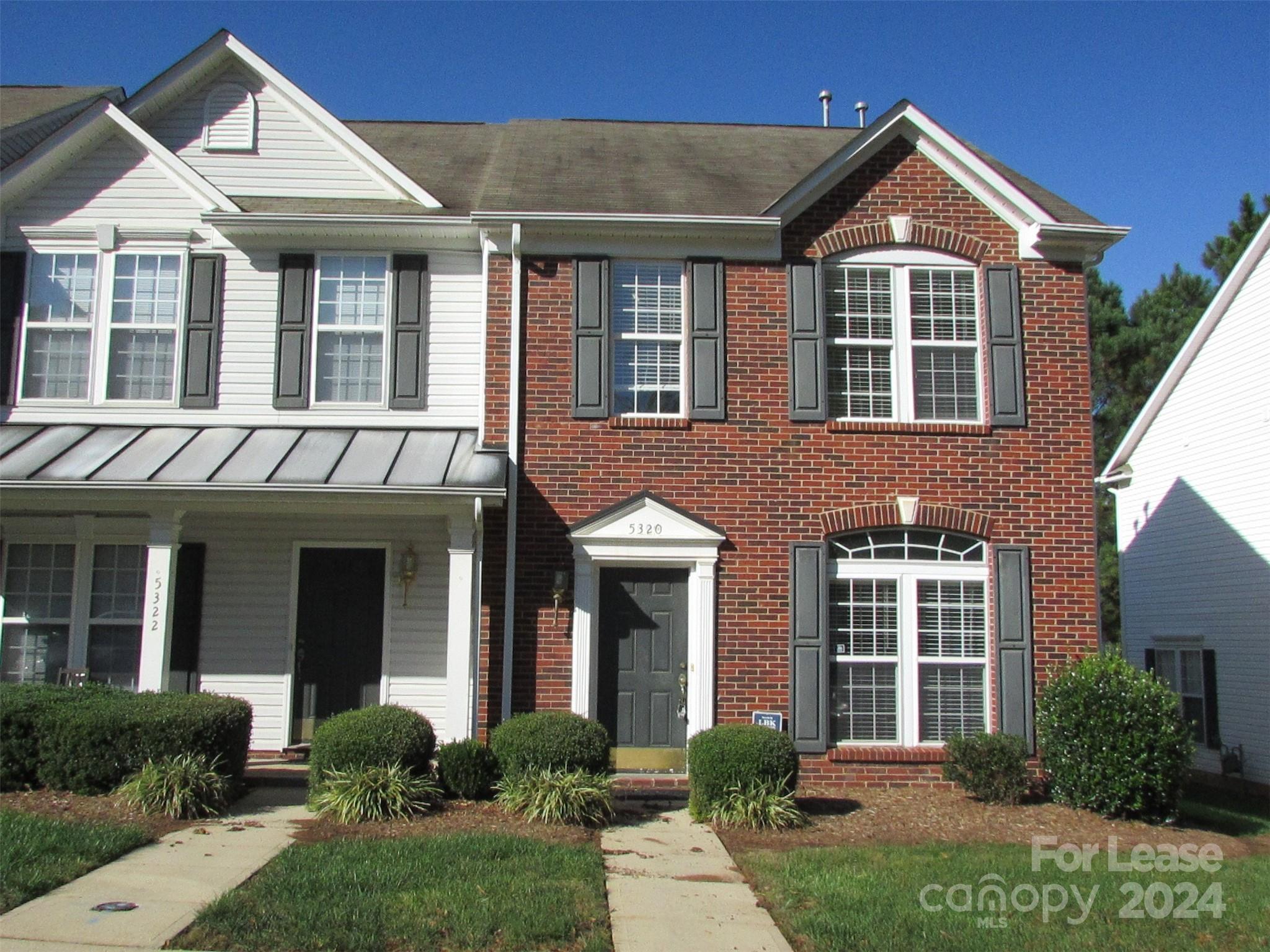 front view of a brick house with a yard