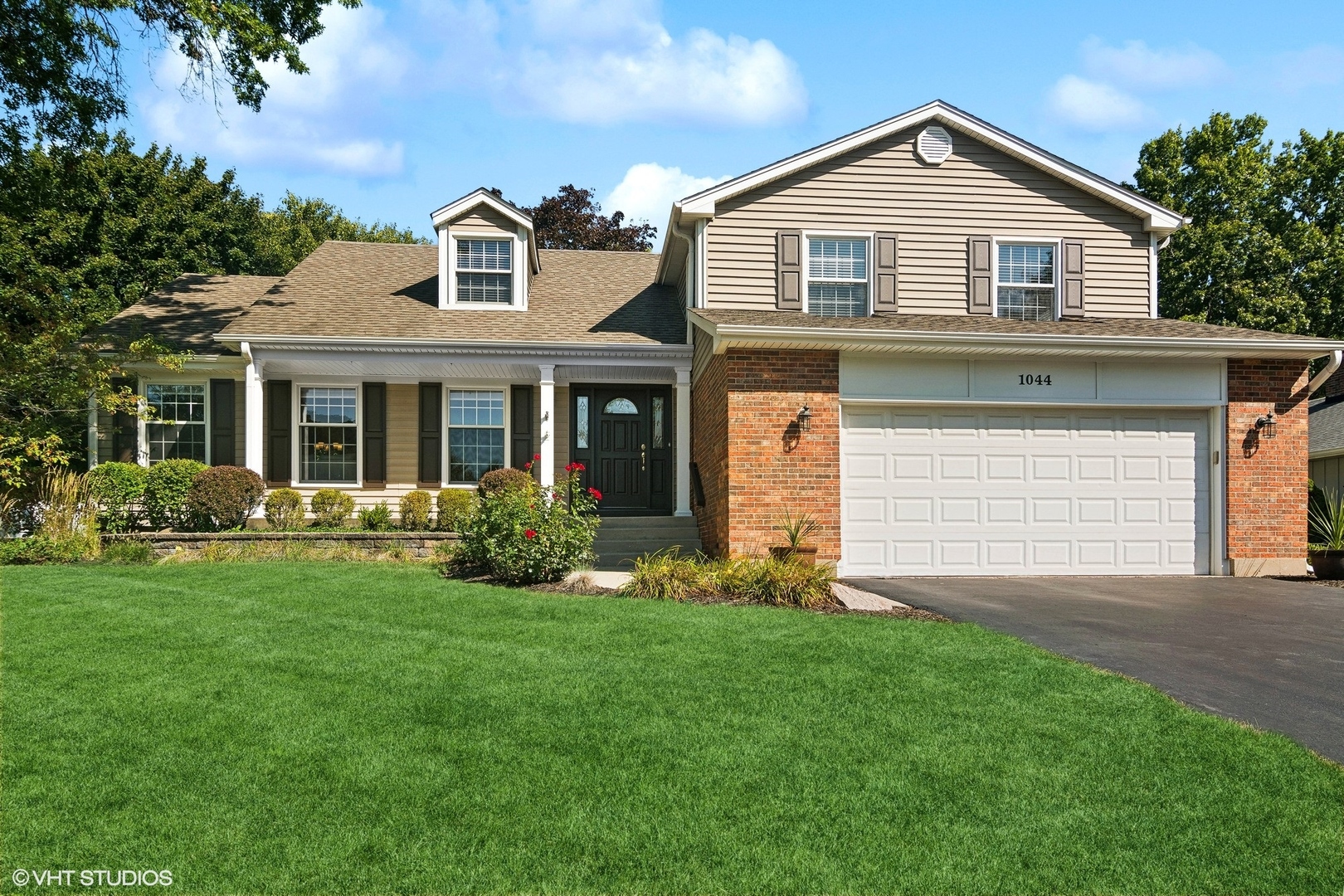 a front view of a house with a garden and yard