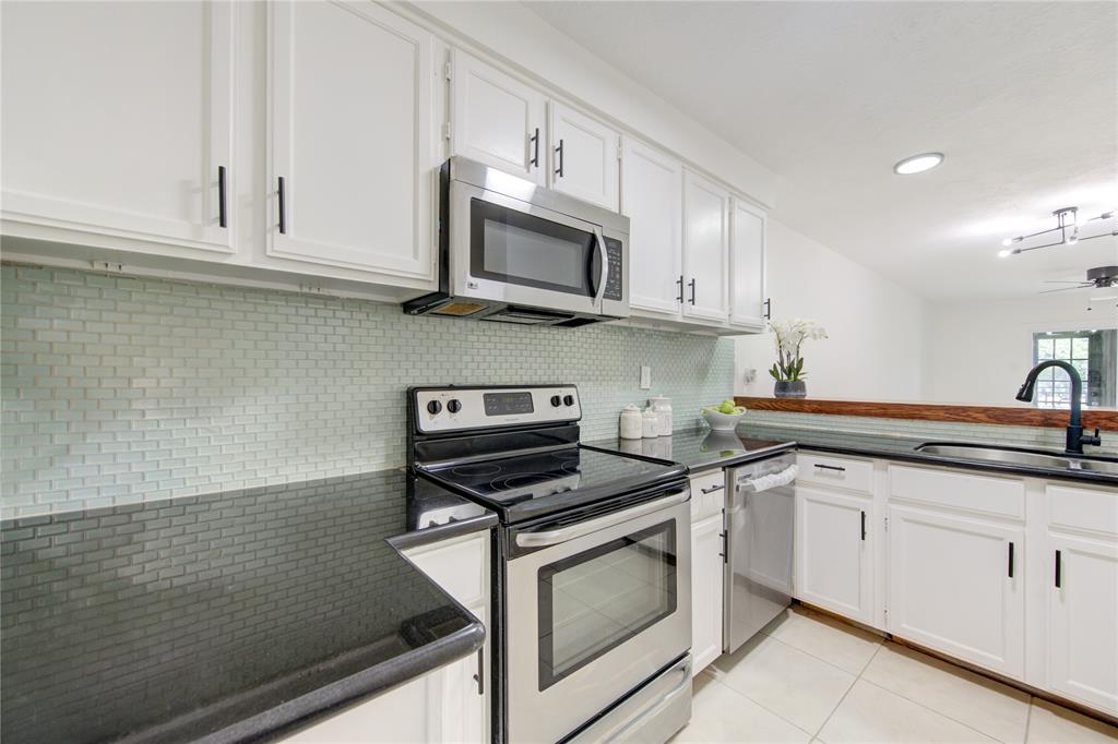 a kitchen with stainless steel appliances granite countertop white cabinets a sink a stove and dishwasher