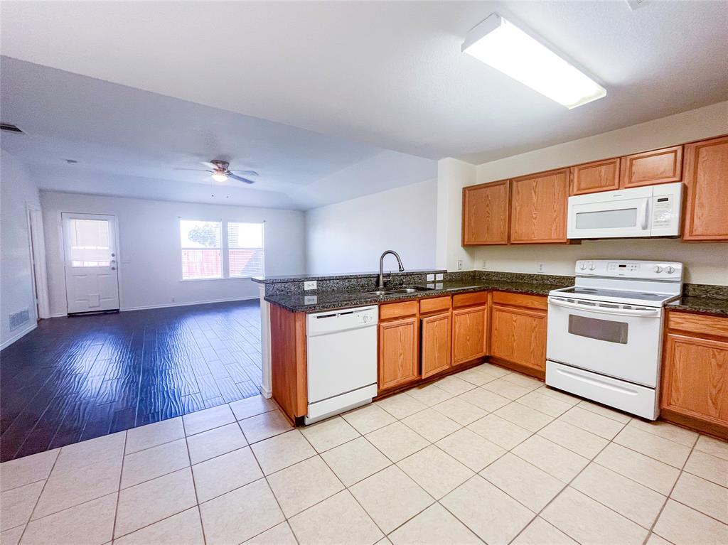 a kitchen with granite countertop cabinets and white appliances