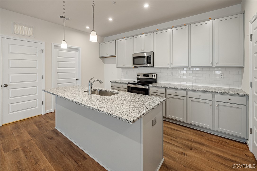 a kitchen with kitchen island granite countertop a sink cabinets and wooden floor