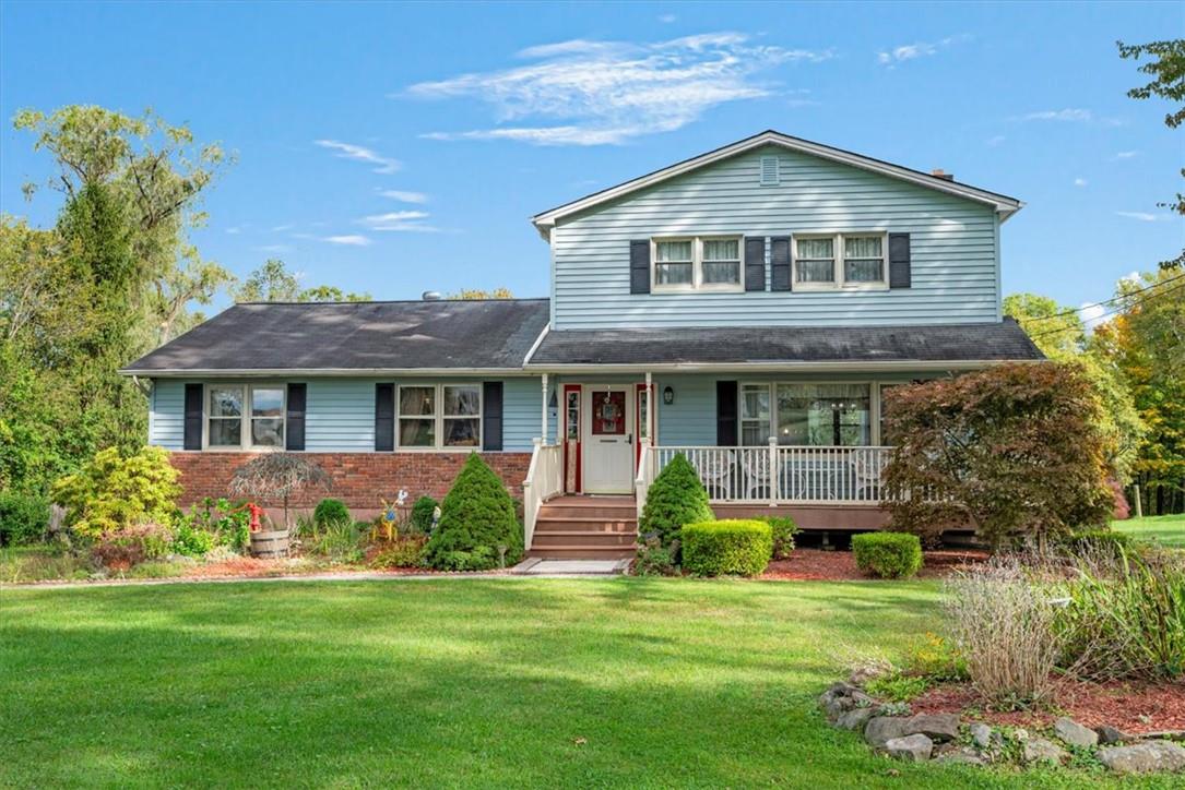 View of property with covered porch and a front yard