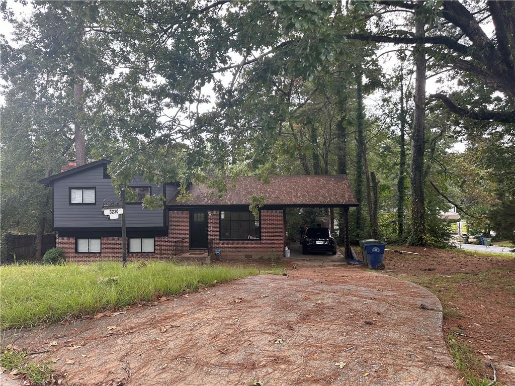 a view of a brick house next to a yard with large trees