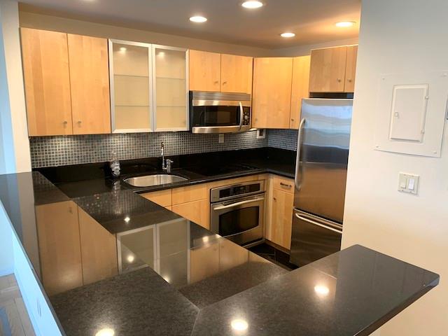 Kitchen with light brown cabinets, sink, and appliances with stainless steel finishes