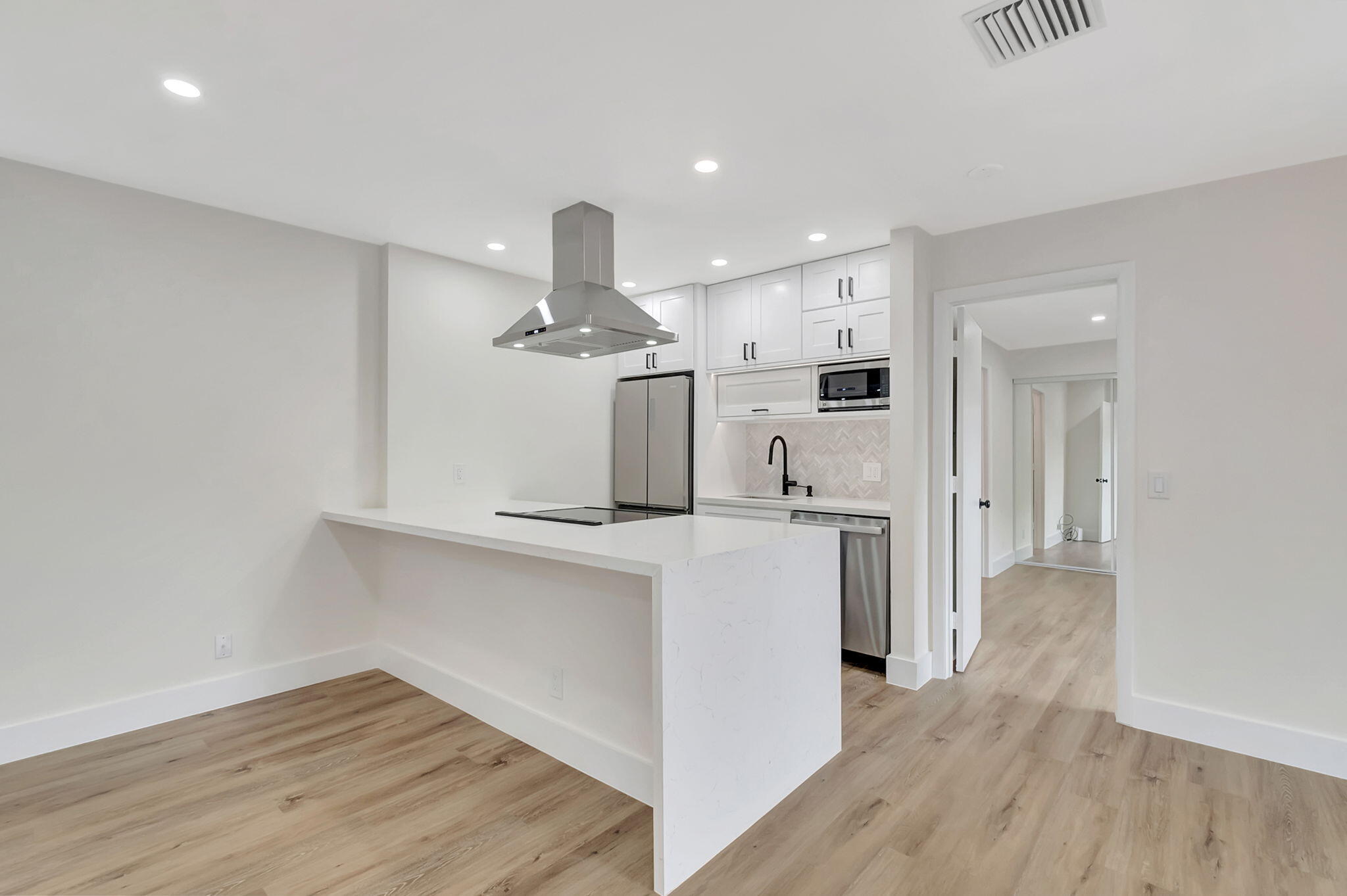 a view of a kitchen with refrigerator and wooden floor