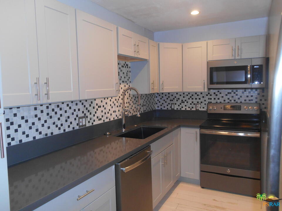 a kitchen with granite countertop white cabinets and black stainless steel appliances