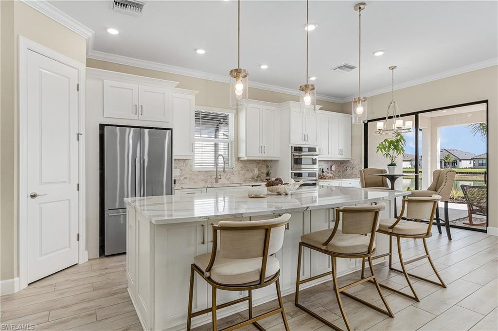 Kitchen featuring a wealth of natural light, a kitchen island, pendant lighting, and white cabinetry