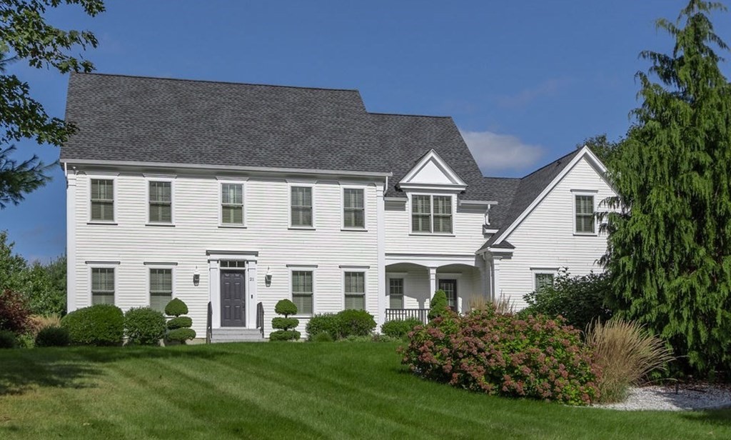 a view of a white house next to a yard with big trees