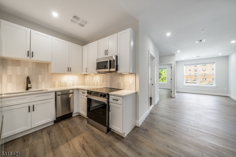 a large kitchen with cabinets wooden floor and stainless steel appliances