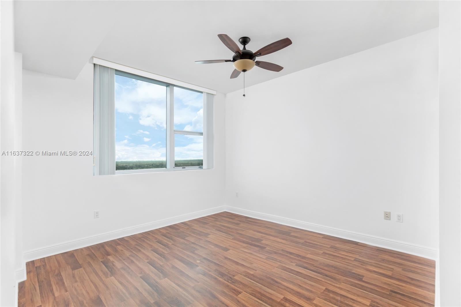 a view of a room with wooden floor and a ceiling fan