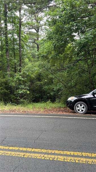 a view of a car parked on the side of a road with trees