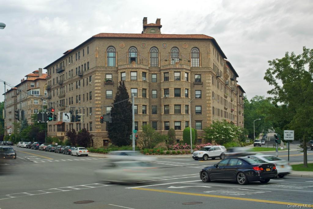 a front view of a building with lot of cars and trees