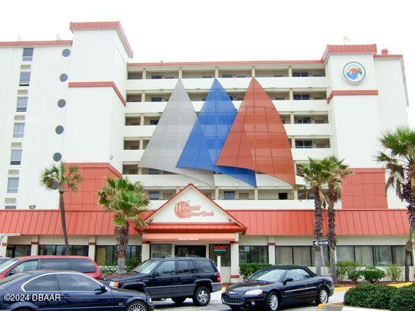 a front view of a building with cars parked