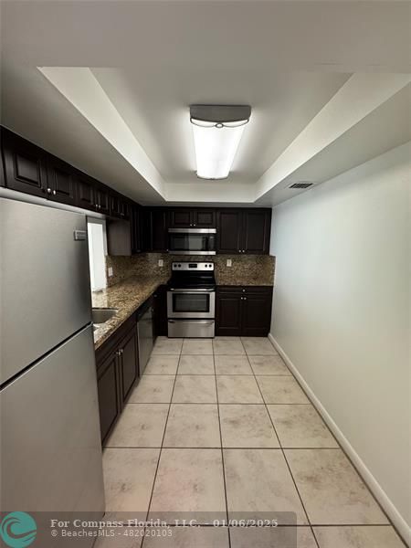 a kitchen with granite countertop a refrigerator and a stove