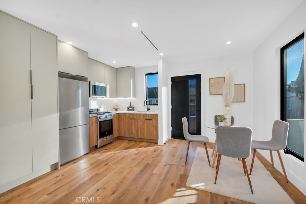 a kitchen with stainless steel appliances refrigerator wooden floor dining table and chair