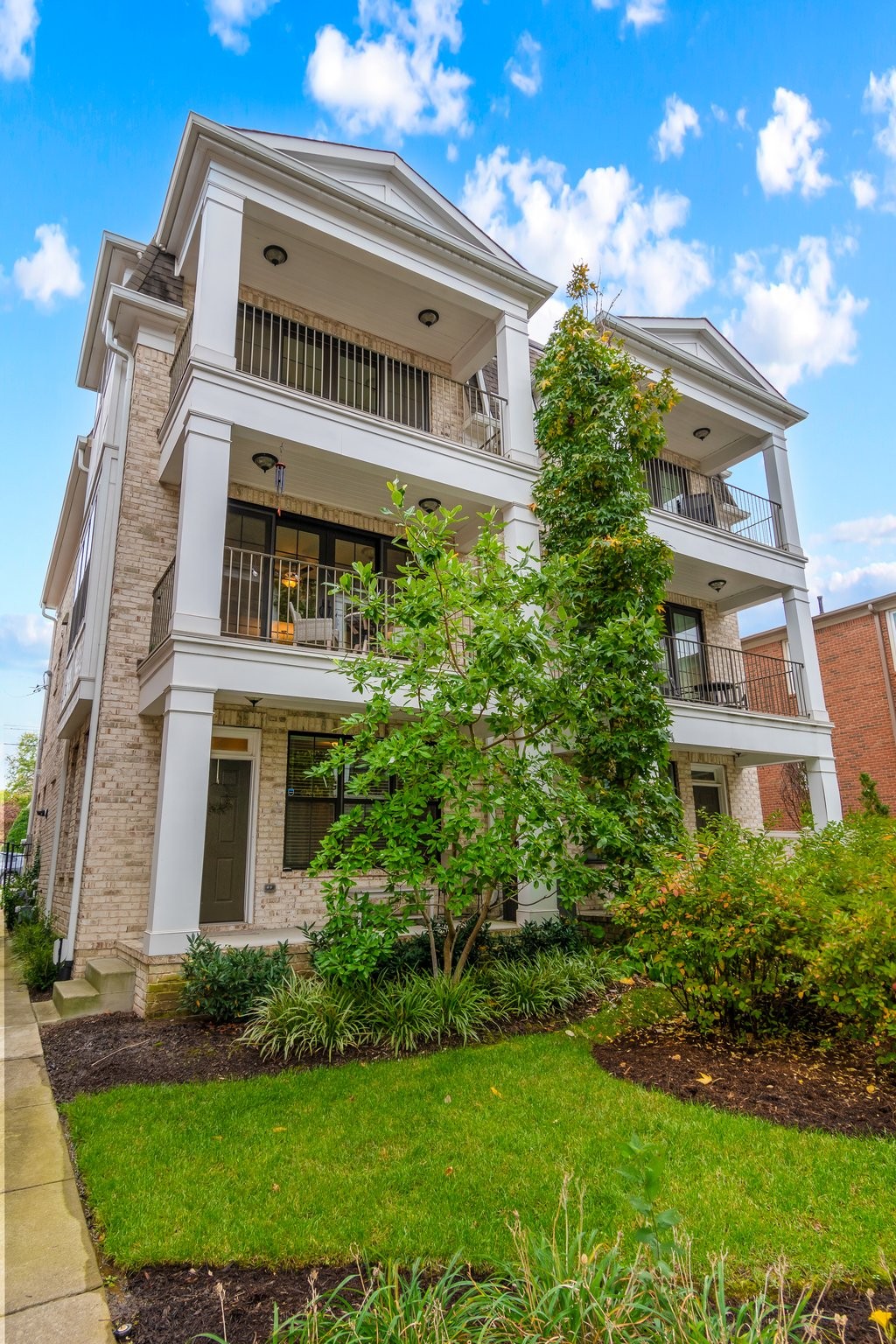 a front view of a multi story residential apartment building with yard and green space