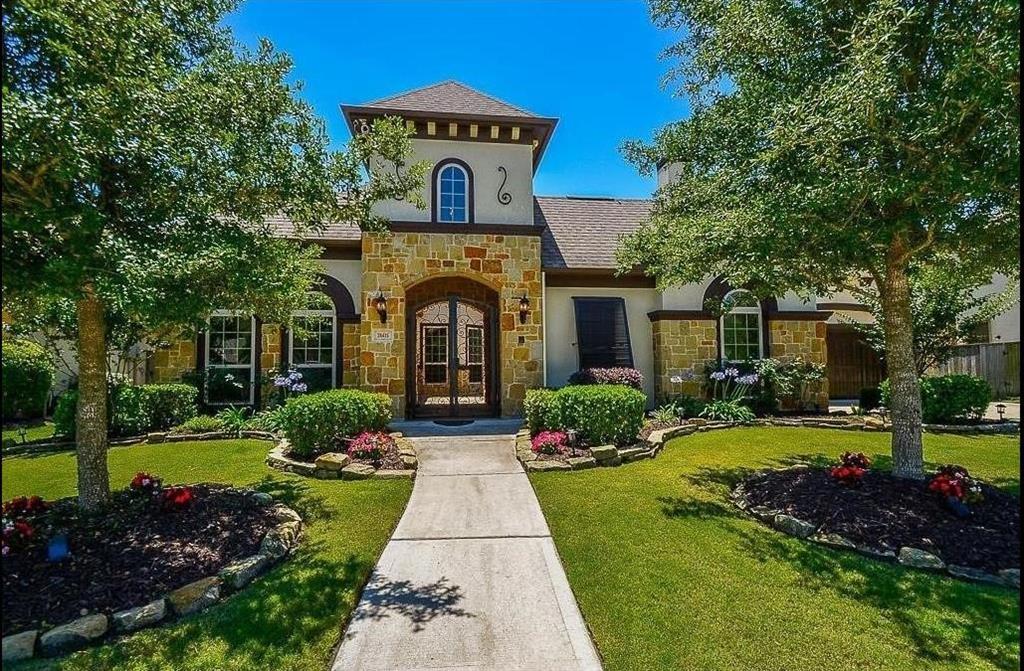 Front view of this gorgeous home with beautiful architectural features including beautiful front doors with wrought iron including transom.