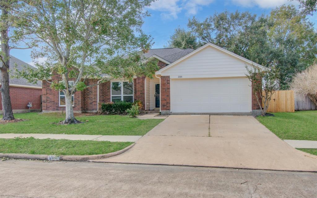 front view of house with a yard and trees all around