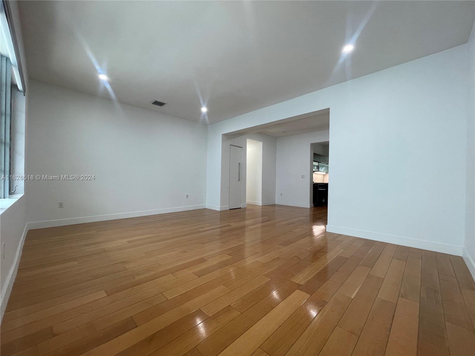 an empty room with wooden floor and natural light