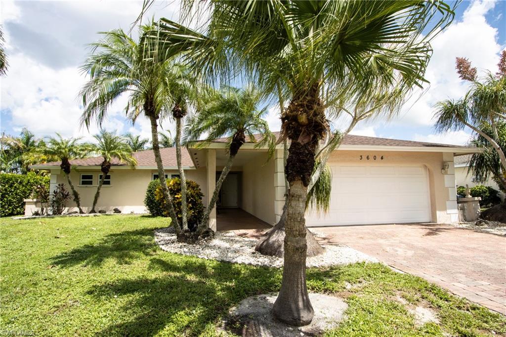 a view of a house with a yard and palm trees