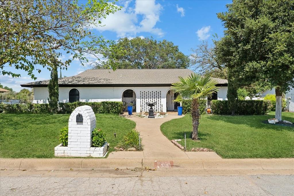 a front view of a house with a garden and trees