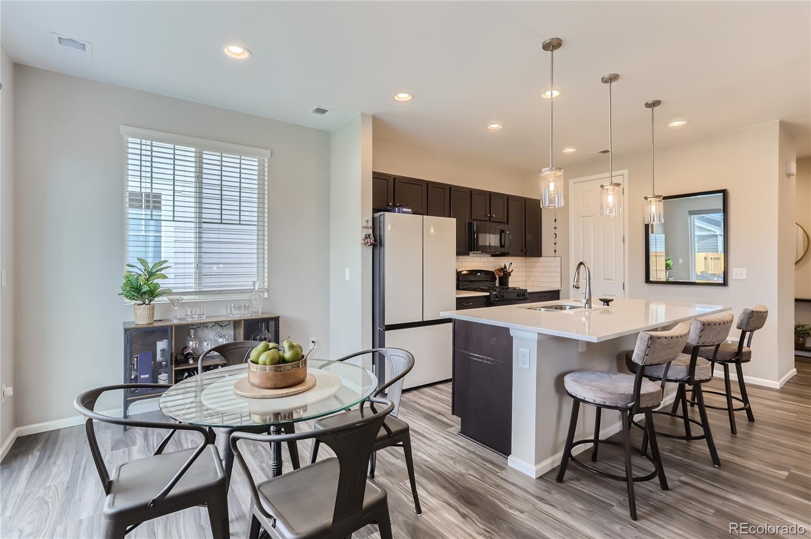 a kitchen with stainless steel appliances kitchen island granite countertop a dining table chairs and white cabinets