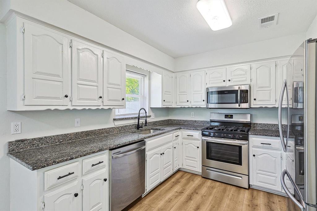 a kitchen with stainless steel appliances granite countertop a stove a sink and a microwave